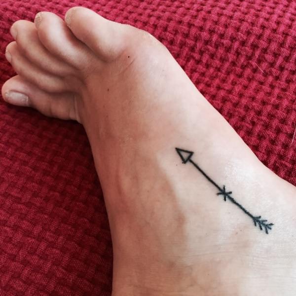 Black Ink Small Arrow Tattoo On Foot