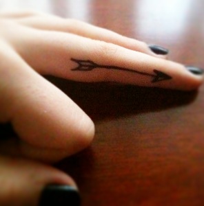 Black Inked Arrow Tattoo On Middle Finger