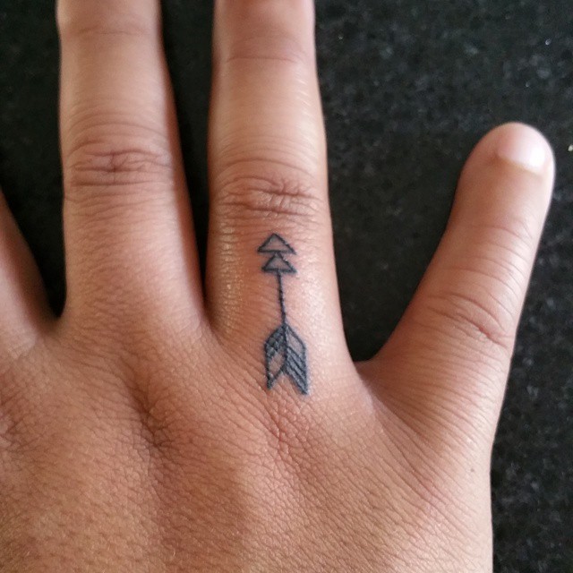 Black Inked Small Arrow Tattoo On Finger