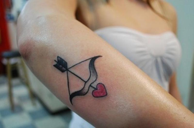 Cute Bow And Heart Headed Arrow Tattoo On Forearm For Women