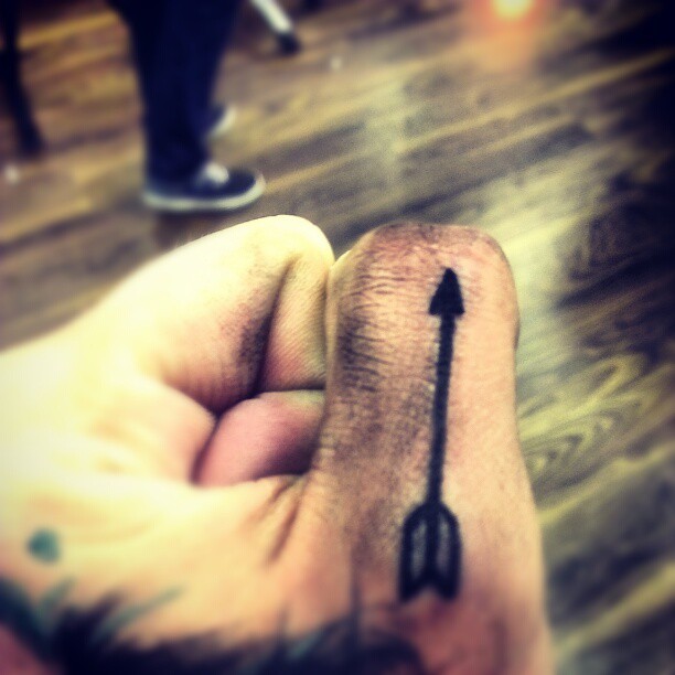 Dark Black Inked Arrow Tattoo On Thumb