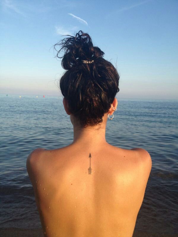 Small Arrow In Black Color Tattoo On Upper Back
