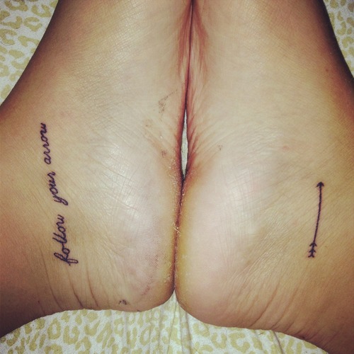 Tiny Arrow On One Foot With Wording On Other Foot Tattoos