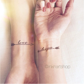 Two Black Arrows With Love And Hope Tattoo On Two Wrist