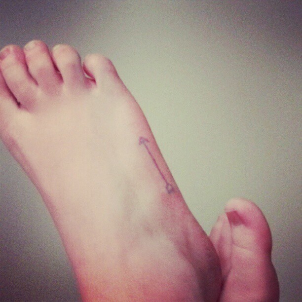 Very Simple And Small Arrow Tattoo On Foot