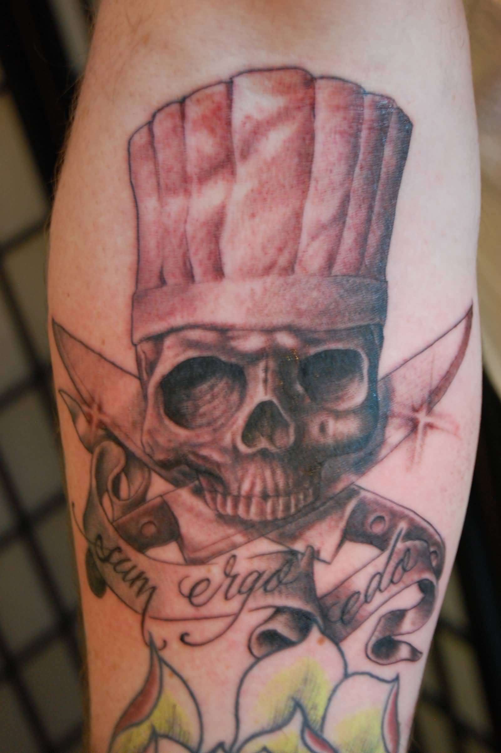 Chef Skull Holding Knife With Mouth And Lettering Tattoo On Forearm