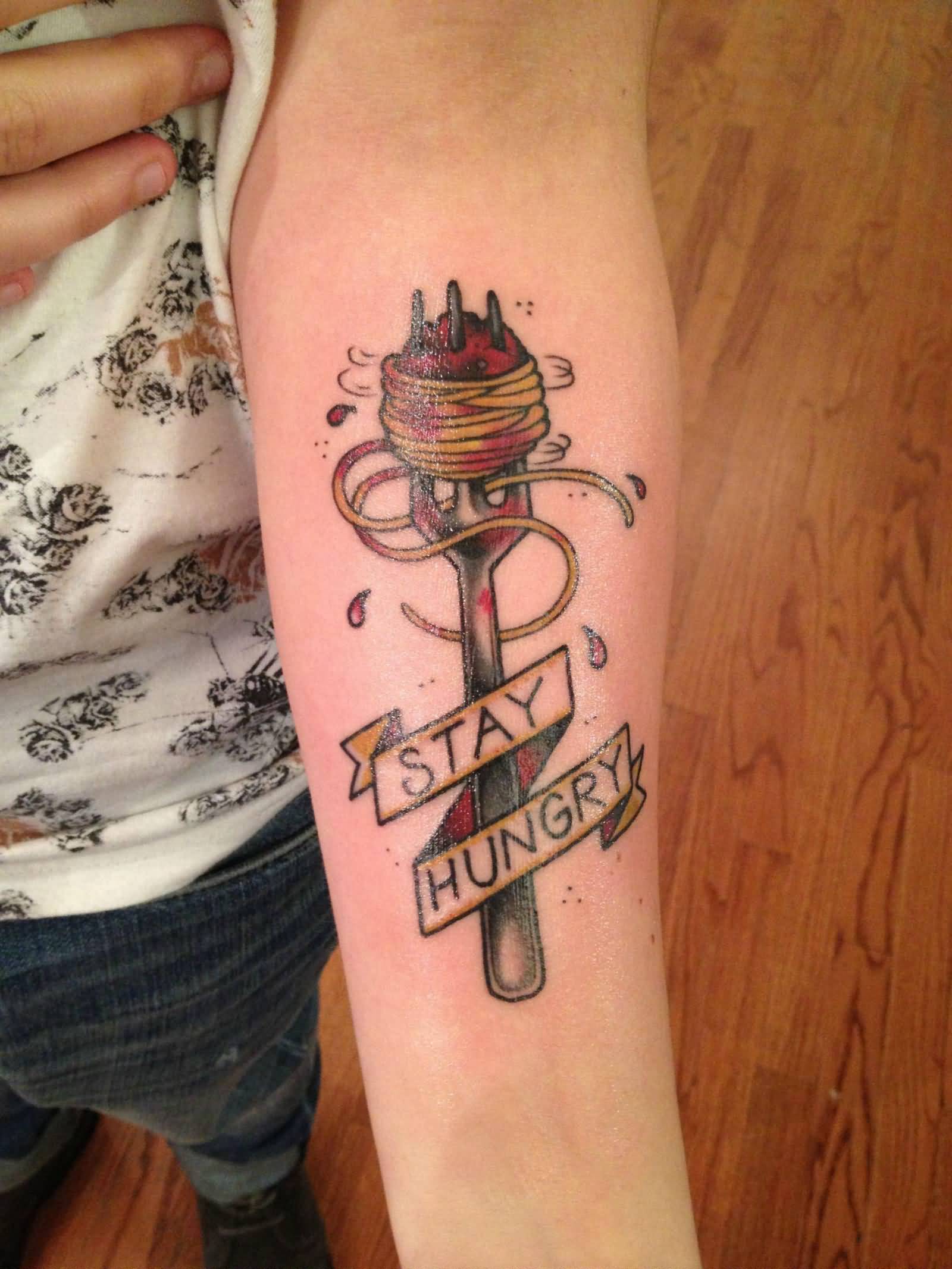 Fork With Noodles And Stay Hungry Banner Tattoo On Forearm