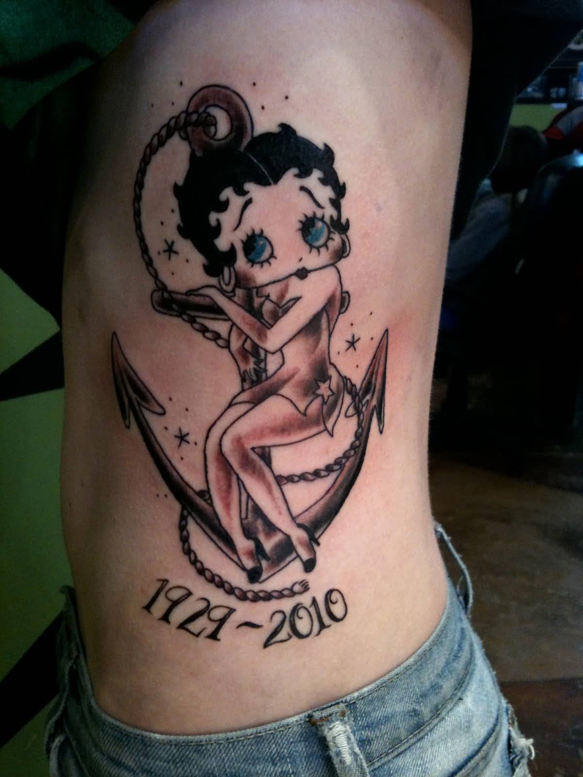 Grey Ink Memorial Anchor And Betty Boop Tattoo On Side Rib