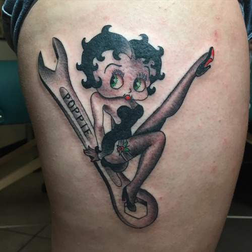 Grey Ink Spanner And Betty Boop Tattoo On Side Thigh