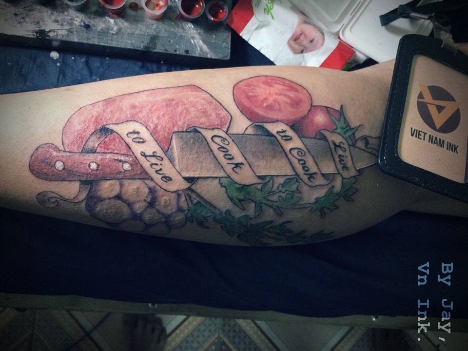 Superb Chef Knife With Vegetables And Lettering On Banner Tattoo On Forearm