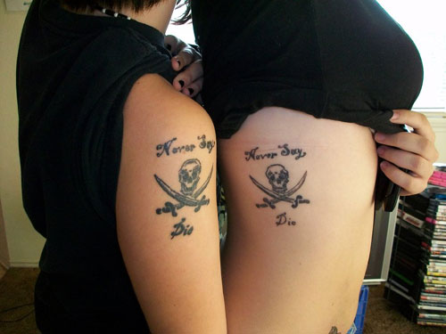 Small Skull With Crossed Swords And Lettering Matching Tattoos On Side Rib And Shoulder