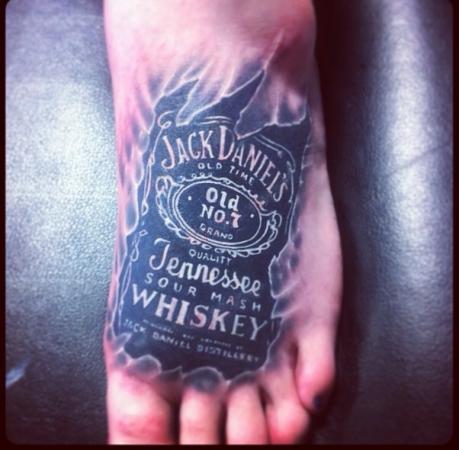Stylized Jack Daniel Label Tattoo On Foot