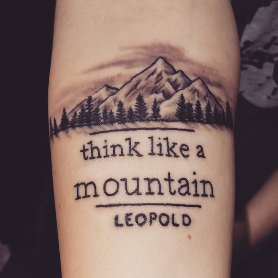Superb Mountains With Trees And Lettering Tattoo On Forearm