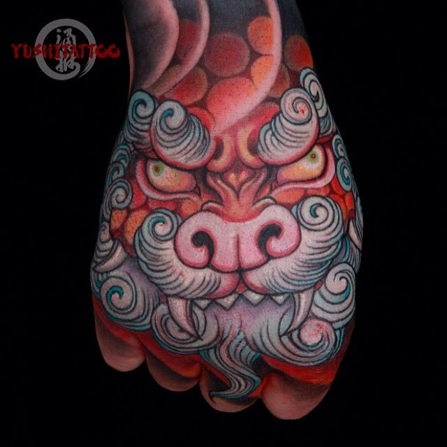 Red And Blue Colored Chinese Foo Dog Face Tattoo On Hand