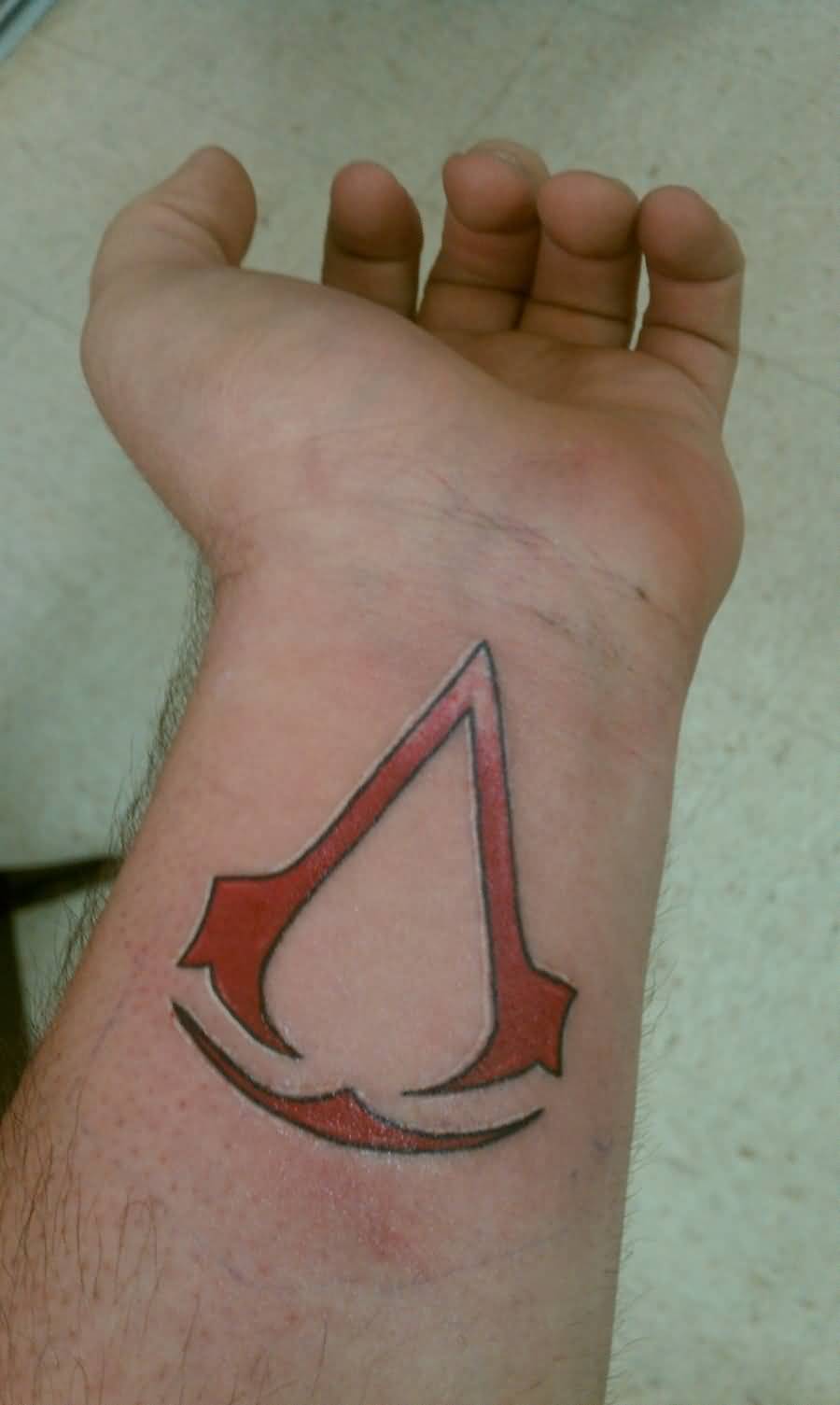 Red Ink Assassins Creed Tattoo On Wrist
