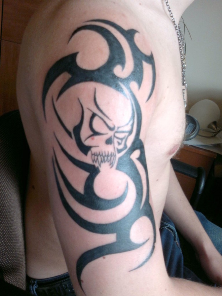Terrific Skull With Tribal Design Tattoo On Right Half Sleeve