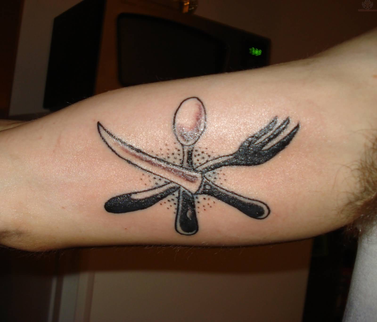 Black And Grey Crossed Fork With Knife And Spoon Tattoo Design On Bicep
