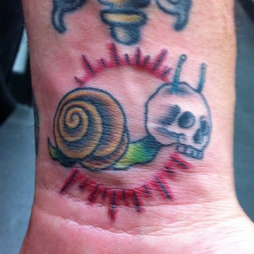Small Skull Headed Snail Colored Tattoo On Wrist