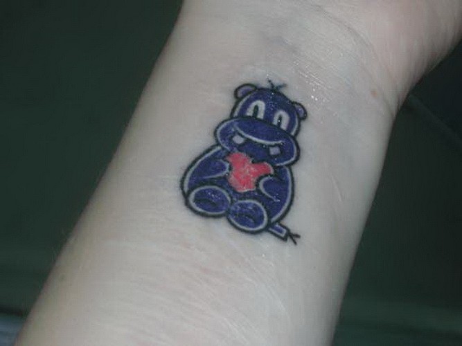 Tiny Cute Violet Hippo Holding Heart Tattoo On Wrist