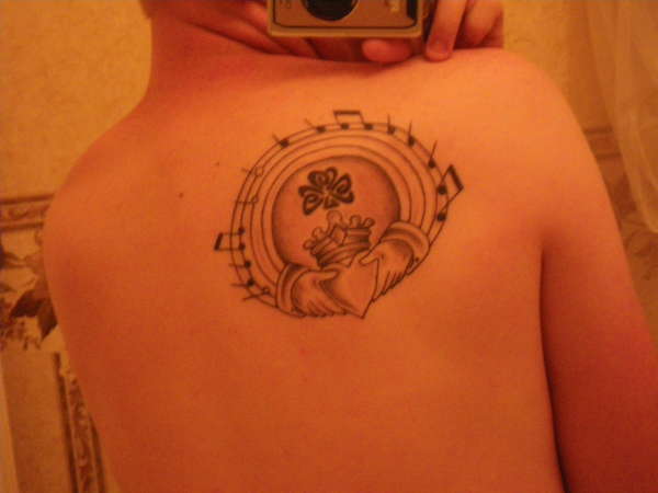 Brilliant Claddagh Shamrock And Musical Score Tattoo On Upper Back