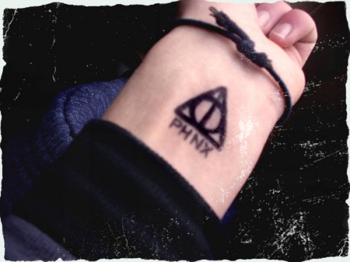 Dark Black Hallows With Lettering Tattoo On Wrist