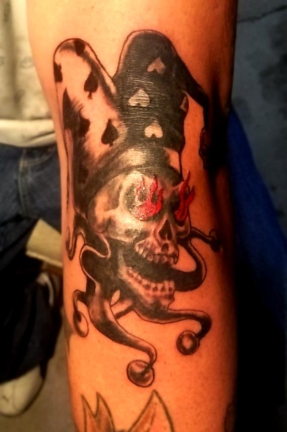 Grey And Black Jester Skull With Flames In Eyes Tattoo On Arm Sleeve