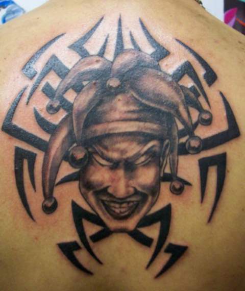 Grey Ink Evil Jester Face And Tribal Design Tattoo On Upper Back