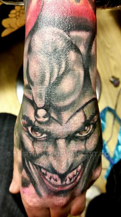 Grey Ink Evil Jester Face Tattoo On Hand And Wrist