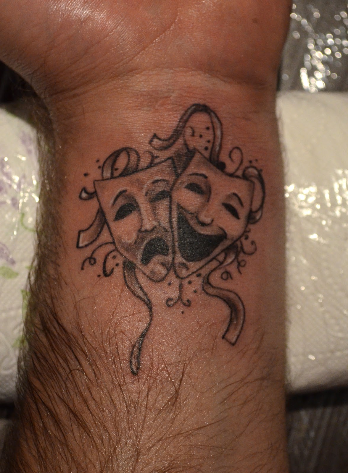 Grey Ink Jester Masks Tattoo On Wrist