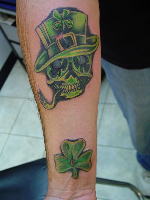 Lovely Green Color Skull Wearing Hat With Shamrock Tattoo On Forearm