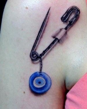 Safety Pin And Turkish Evil Eye Tattoo On Shoulder