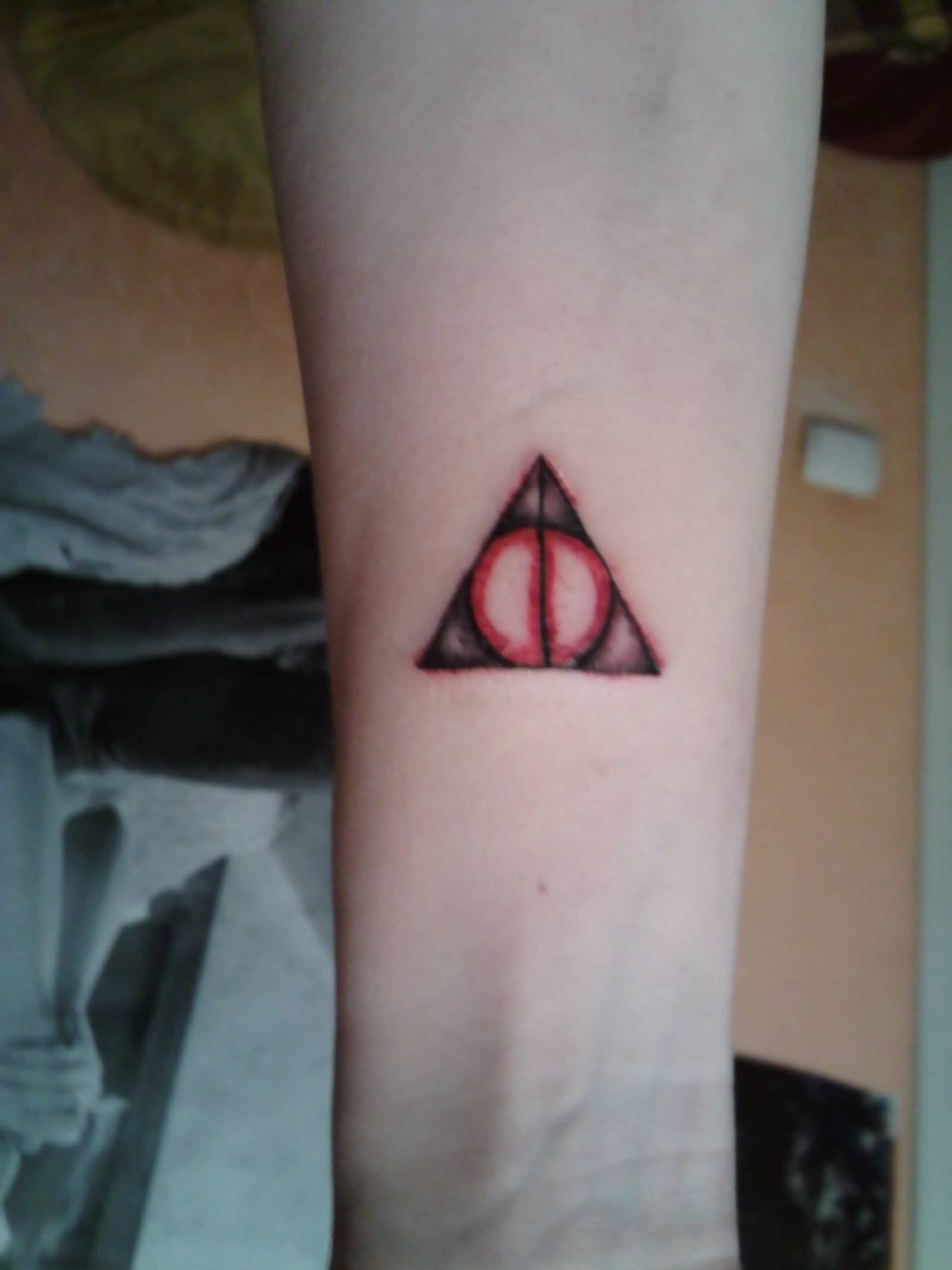 Small Red And Brown Hallows Tattoo On Forearm