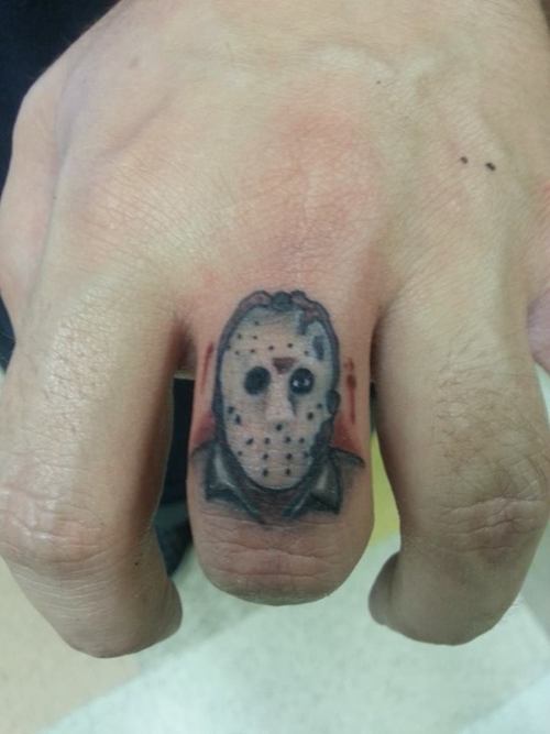 Tiny Colored Jason Head Tattoo On Finger