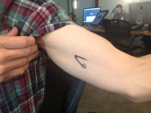 Tiny Simple Safety Pin Tattoo On Biceps