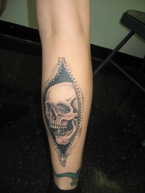 Black And Grey Skull In Zipper Tattoo On Back Leg