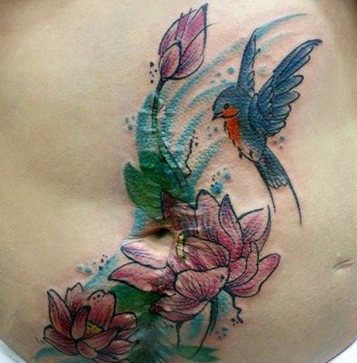 Lovely Flying Bird With Flowers Plant Tattoo