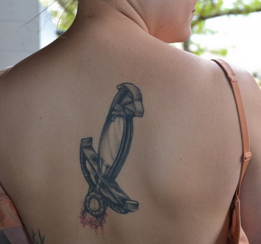 Nice Black Knife Half In Skin Tattoo On Back For Girls
