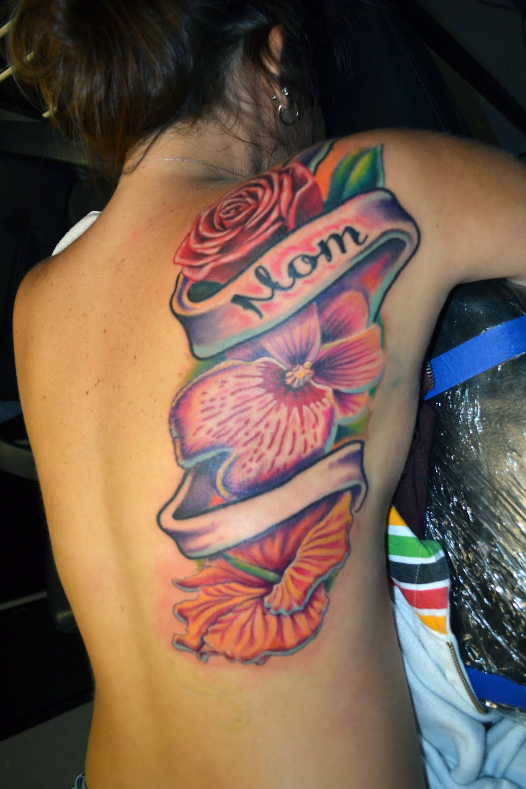 Beautiful Large Flowers With Mom Banner Tattoo On Upper Back For Girls