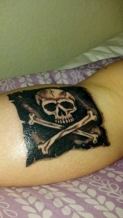 Black And Grey Jolly Roger Flag Tattoo On Forearm
