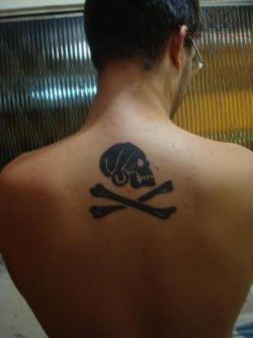 Black Jolly Roger Skull Looking At Right Side Tattoo On Upper Back