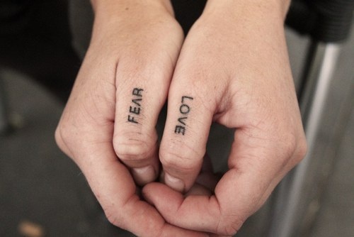 Fear And Love Tattoos On Both Thumbs