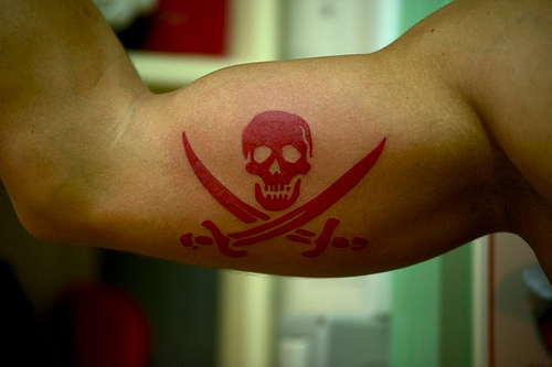 Red Color Jolly Roger Tattoo On Biceps