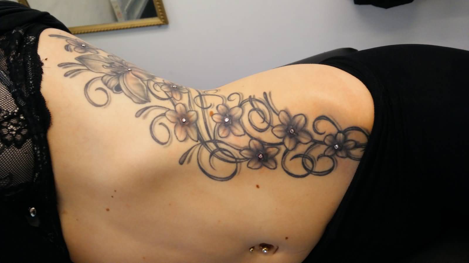 Black And Grey Flower Tattoos On And Dermal Anchoring Piercing On Side Rib