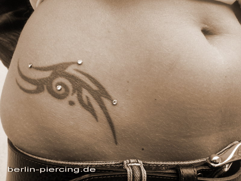 Black Tribal And Dermal Anchoring Piercing On Right Hip