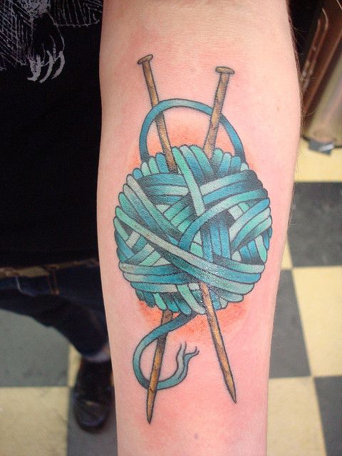 Blue Knitting Needles In Yarn Ball Tattoo On Forearm