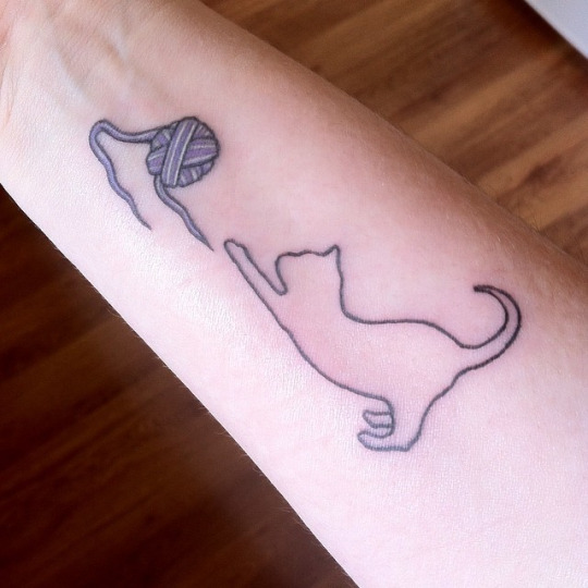 Cat Outline With Yarn Ball Tattoo On Forearm