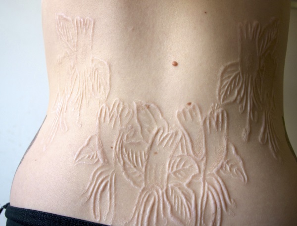 Flowers Scarification Tattoo On Lower Back For Women