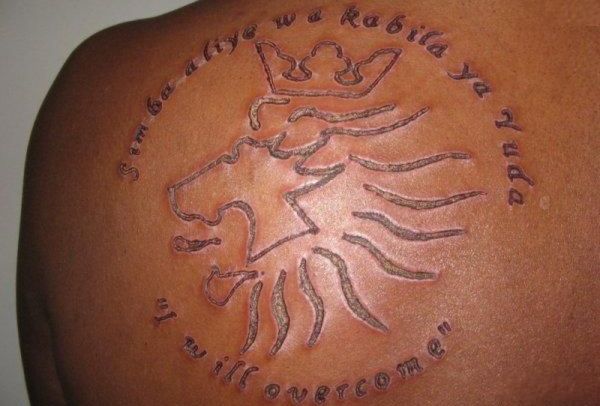Lion Symbol With Lettering Scarification Tattoo