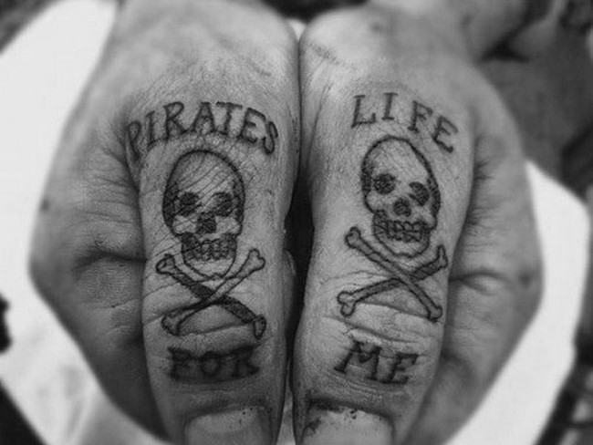 Tiny Pirate Skull With Lettering Tattoos On Both Thumbs