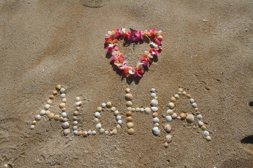 Aloha Written With Sea Shells On Beach Sand With Flowers Garland